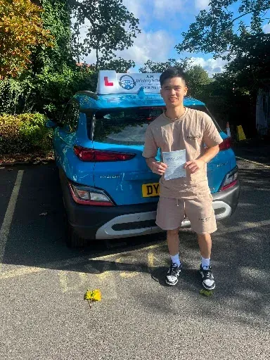 Thuy holding pass certificate in front of tuition car