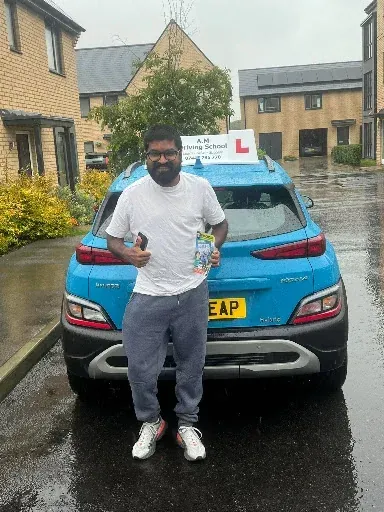 Vighnesh proudly holding test certificate next to tuition car